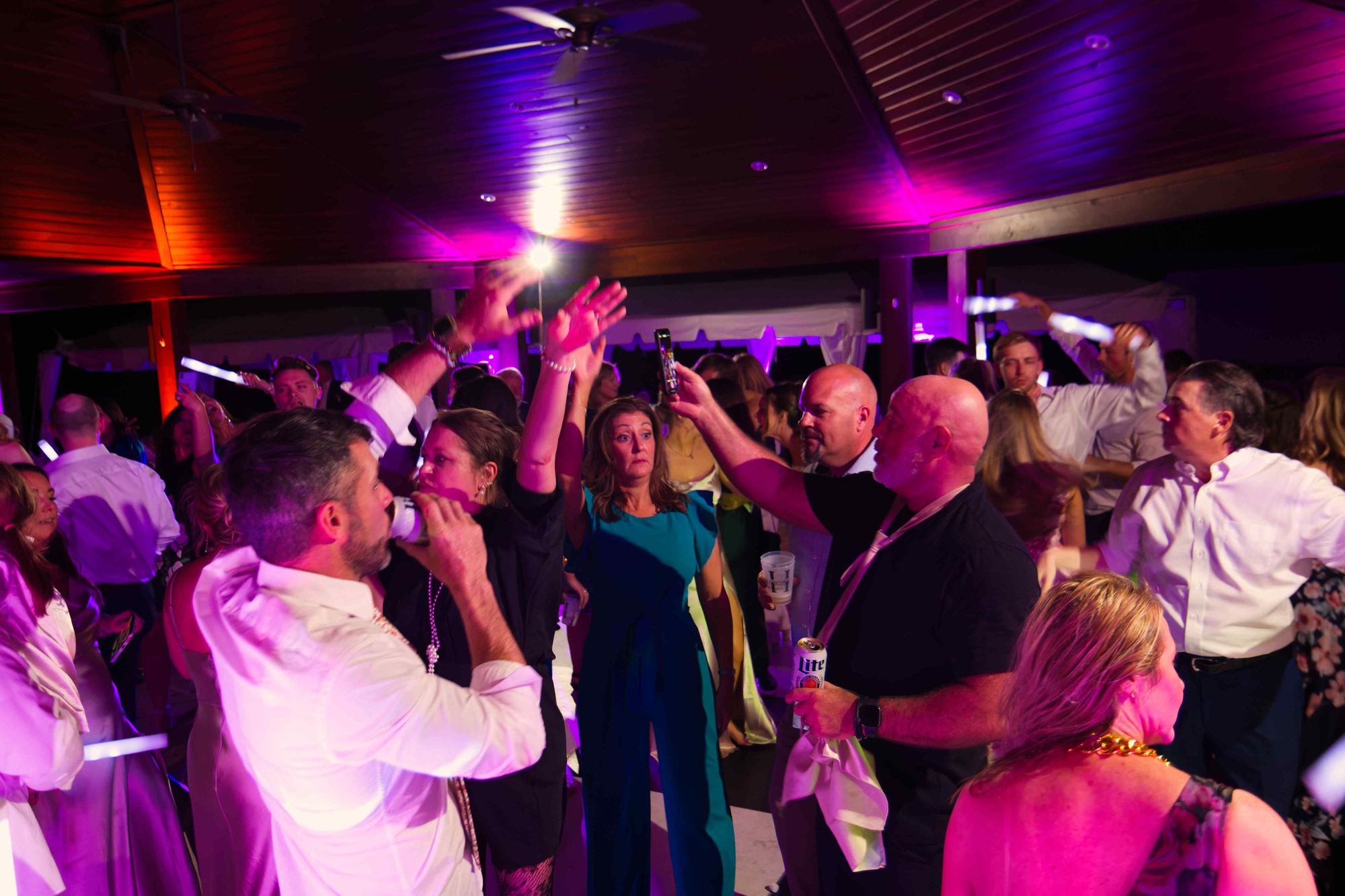 Guests with their hands and light sticks in the air under magenta light