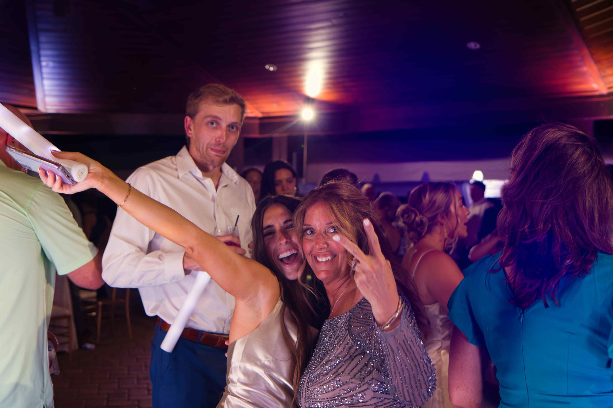 Guests laughing together on the dance floor, light sticks in hand