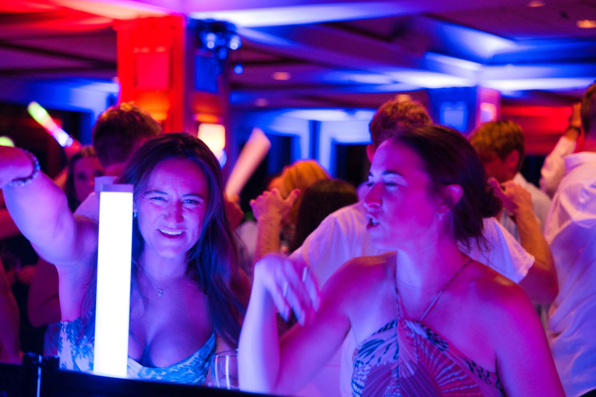 Guests mid-laugh on the floor, the room lit in red and blue