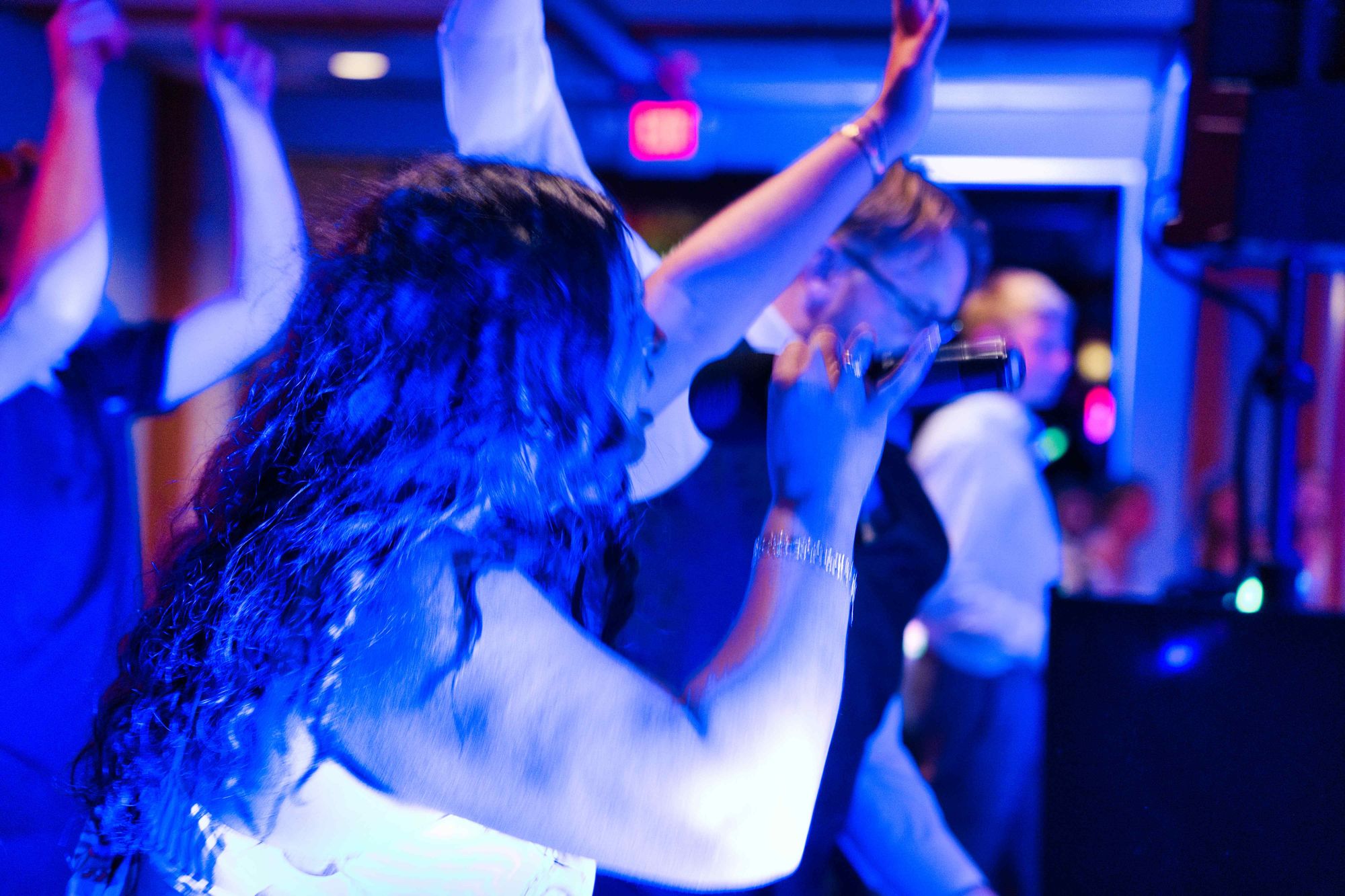 A guest dancing with her arms raised, the booth just visible at the edge of frame